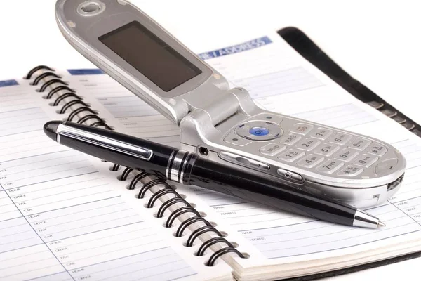 Old cell phone and pen sitting on a address book