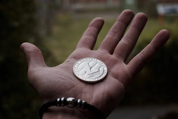 デジタル通貨物理的な銀 Litecoin コイン ブレスレット 黒男の手 — ストック写真