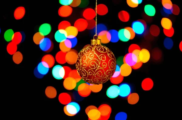 Bauble Natal Ornamentado Pendurado Contra Fundo Preto Com Luzes Coloridas — Fotografia de Stock