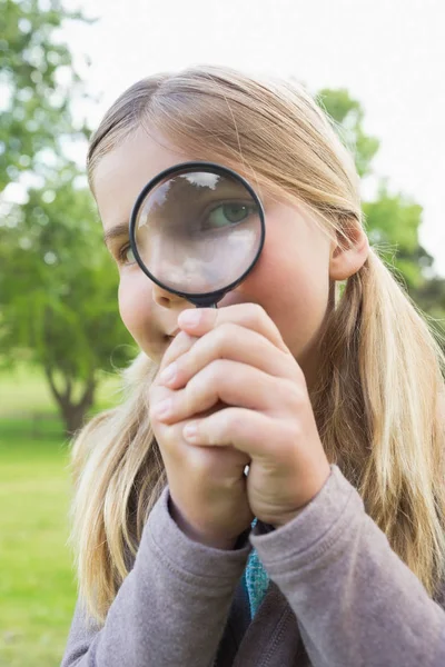 公園で虫眼鏡を通して見ているかわいい少女のクローズアップ肖像画 — ストック写真