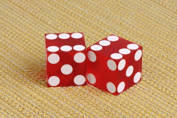 Authentic casino dice on golden striped fabric.