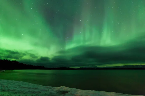 ラバージュ湖 ユーコン準州 カナダの曇り夜空の冬のシーンにオーロラボレアリスやオーロラの緑の輝くショー — ストック写真