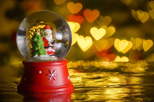 Weihnachten Schneekugel Mit Weihnachtsbeleuchtung Hintergrund Weihnachtsmann Mit Christbaum Herzformen Bokeh — Stockfoto