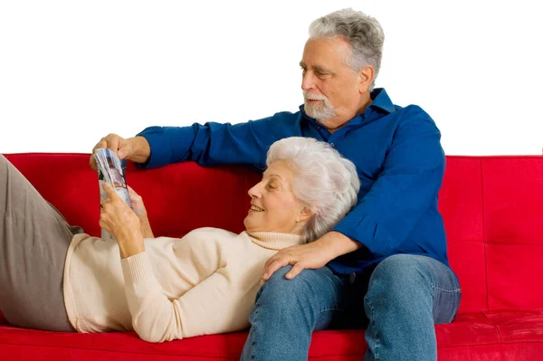 在沙发上读一本杂志对老年夫妇 — 图库照片