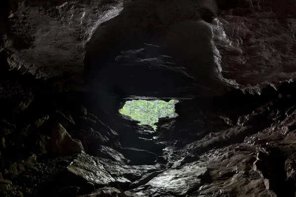 在黑暗潮湿的洞穴里 有光的出口在视野中 — 图库照片