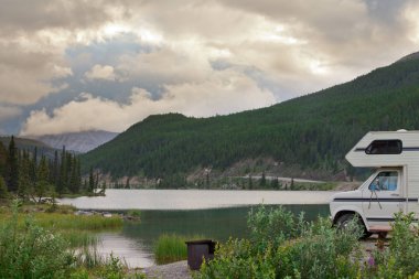 Camper van parked on Summit Lake Campground in Stone Mountain Provincial Park, highest point of the Alaska Highway, northern BC, Canada clipart