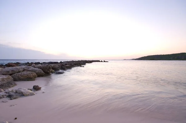 岩波のブレーカーと紫の青い海の夕日 — ストック写真