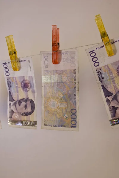 Illustration with the highest denomination of bank notes in Norway, hanging on a clothes hanger with clothes-pegs. Could illustrate money laundering and illegal business, but also a good illustration for wealth and money.