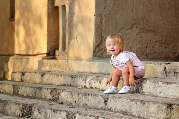 Blond girl with blue eyes sitting on the porch steps
