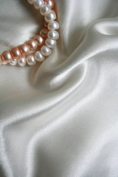 真珠が付いている滑らかな優雅な白いシルクは背景として使用できる — ストック写真