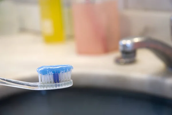 在模糊背景中 带有牙膏的牙刷和盆的详细照片 — 图库照片