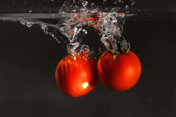 Frische Tomaten Ins Wasser Fallen Gelassen Isoliert Auf Dunklem Hintergrund — Stockfoto