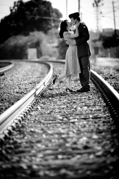 Young woman and World War 2 GI kissing on train tracks