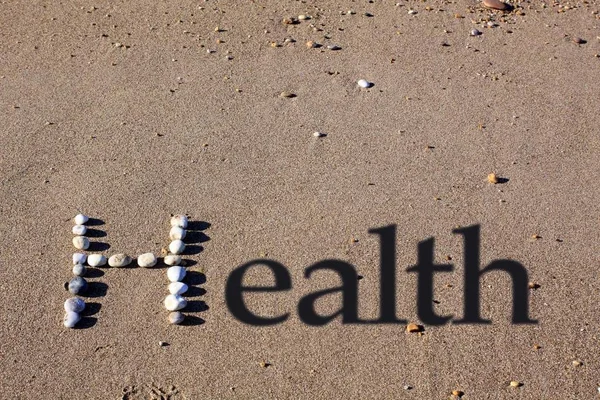 모래에 자갈에 대문자 그림자 텍스트가 추가되어 건강이라는 단어가 스펠트됩니다 — 스톡 사진