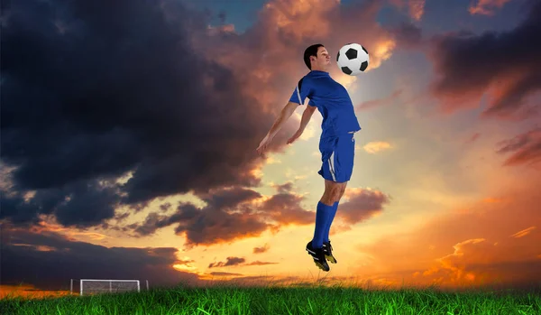 Ποδοσφαιριστής Στην Μπλε Άλμα Κατά Πράσινο Γρασίδι Κάτω Από Γαλάζιο — Φωτογραφία Αρχείου