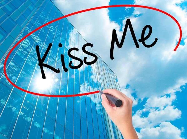 Women Hand writing Kiss Me with black marker on visual screen. Isolated on skyscraper. Business, technology, internet concept. Stock Photo