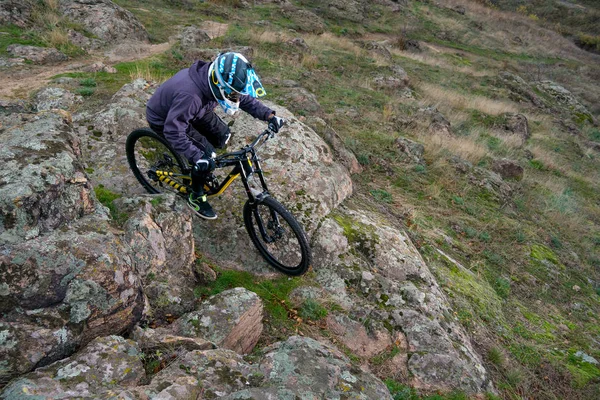 Professional Cyclist Riding the Mountain Bike Down the Rocky Hill. Extreme Sport and Enduro Biking Concept.