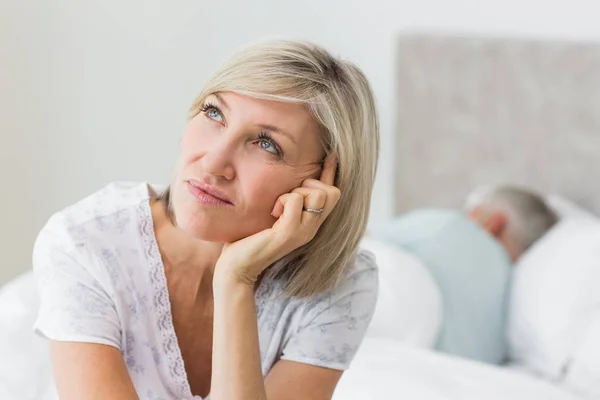 Closeup Tensed Mature Woman Sitting Bed Man Background Home — Stock Photo, Image