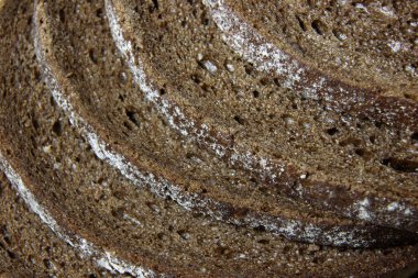 A close-up of the crusts of five slices of pumpernickel bread. clipart