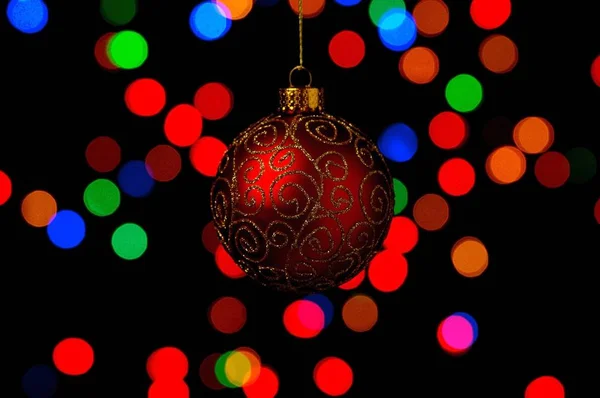 Bauble Natal Ornamentado Pendurado Contra Fundo Preto Com Luzes Coloridas — Fotografia de Stock