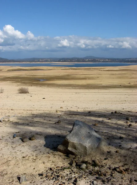 A mostly dry lake bed at Folsom Lake, California, with a storm brewing in the distance.