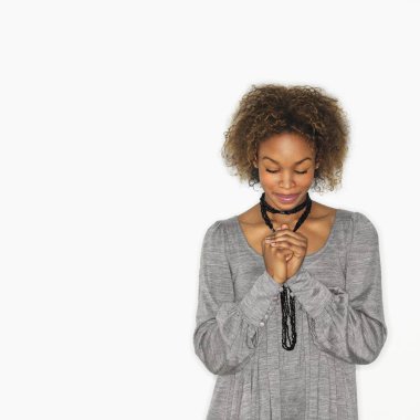Woman with hands clasped together in prayer and eyes closed. clipart
