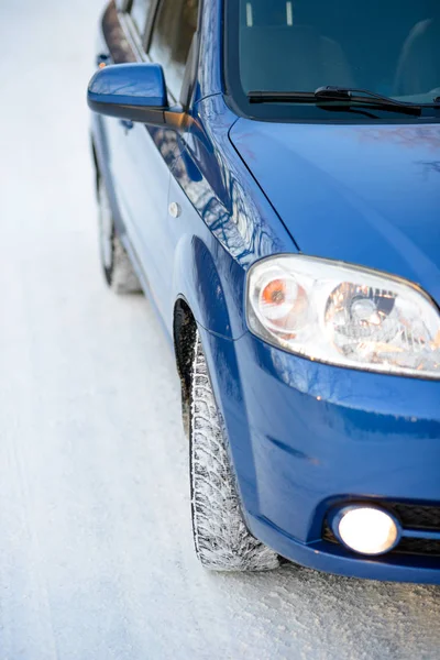 雪地路上的蓝色汽车与冬季轮胎 驱动安全概念 — 图库照片