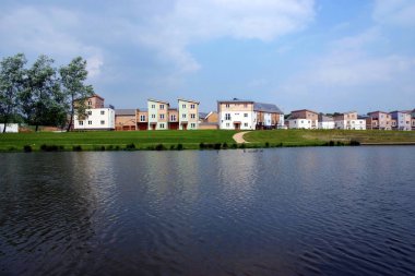 A development of modern housing with a lake in the foreground clipart