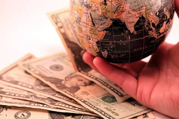 Světová Zeměkoule Americké Peníze Proti Bílému Pozadí Ruka Držela Zeměkouli — Stock fotografie