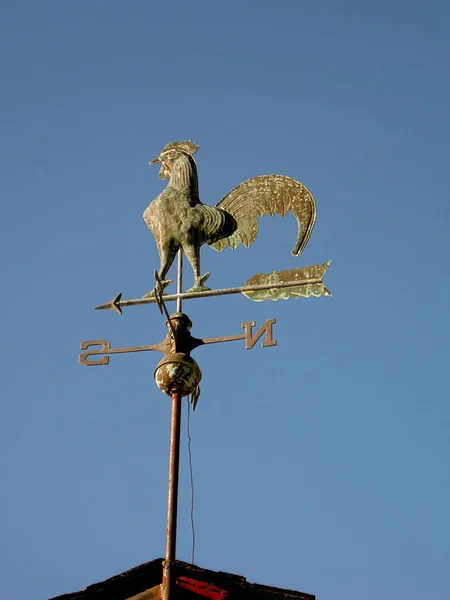 Brass rooster weather vane on farm