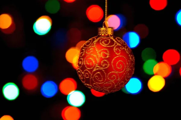 Bauble Natal Ornamentado Pendurado Contra Fundo Preto Com Luzes Coloridas — Fotografia de Stock