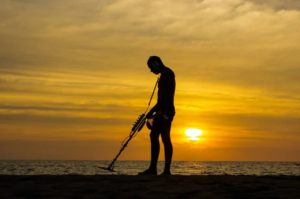 用金属探测仪对日落海滩上的宝藏猎人 — 图库照片