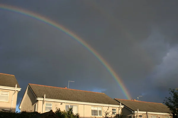 Rainbow in sky above houses