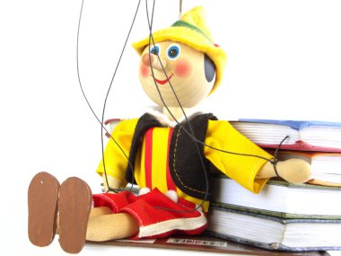 Wooden puppet sitting on the books based on their hands clipart
