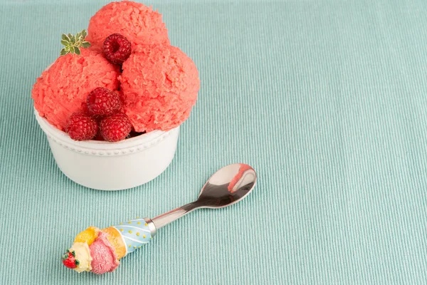 Red fruits ice cream and spoon on table backrground