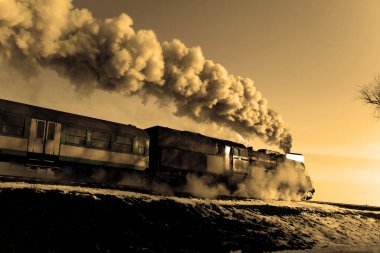 Vintage steam train puffing through countryside during wintertime clipart
