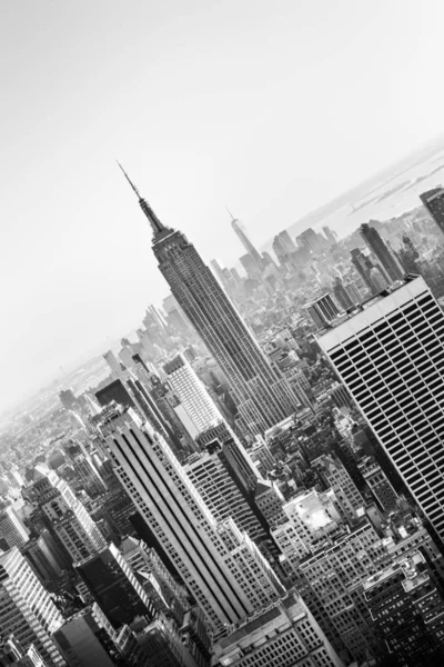ニューヨーク マンハッタンのダウンタウンのスカイラインは 日没時に照らされたエンパイアステートビルと高層ビルがあります 垂直構成 白黒画像 — ストック写真