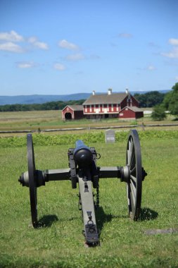 Farm house and cannon on Cemetery Ridge overlook battle site at Gettysburg National Military Park clipart