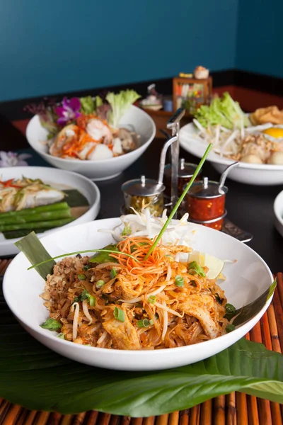 Chicken pad Thai with a variety of other fine Thai food dishes.  Shallow depth of field.