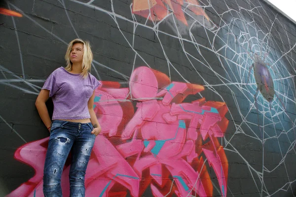 Милая Молодая Блондинка Прислоняется Стене Покрытой Граффити Низкий Угол — стоковое фото