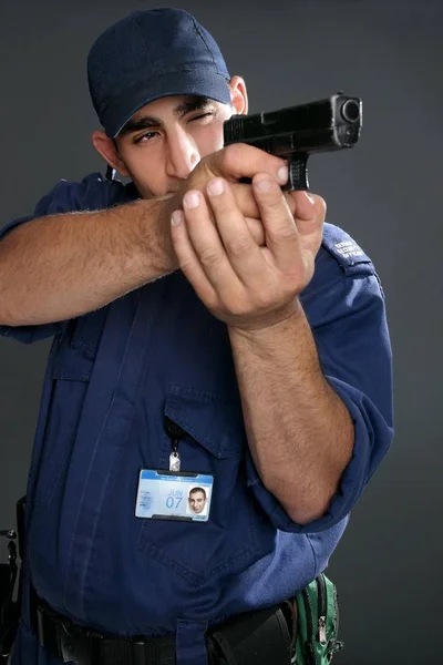 Security guard taking aim with gun.  Please note:  Badge photo is same person and was photographed by me.  No extra release required.