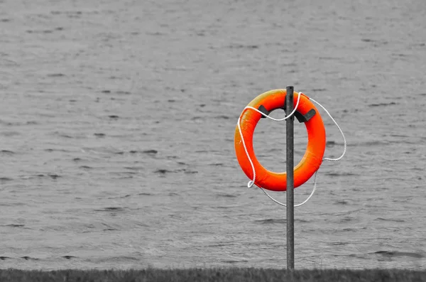 A red rescue ring on the beach. Image B&W, black and white. Image color splash.