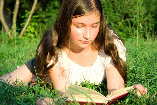 Das Junge Mädchen Liest Das Buch Auf Einem Gras Liegend — Stockfoto