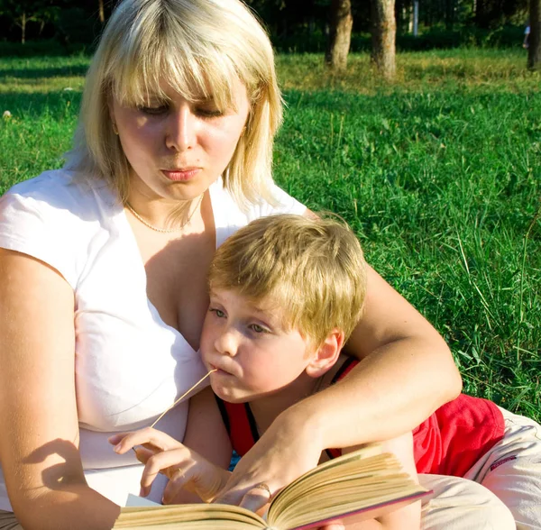 Madre Sienta Sobre Hierba Con Hijo Regazo Lee Muchacho Libro — Foto de Stock