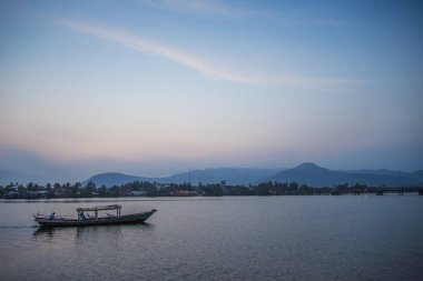 boat at sunset in kampot riverside cambodia clipart
