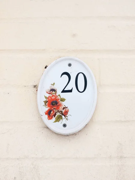 house number plate on outside white wall number 20 flower design  essex  england  uk