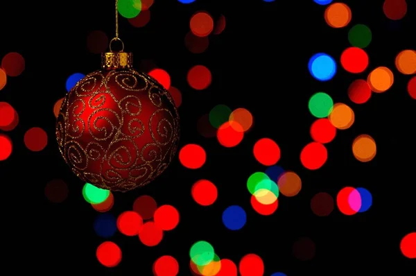 Bauble Natal Ornamentado Pendurado Contra Fundo Preto Com Luzes Coloridas — Fotografia de Stock