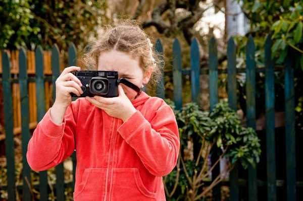 年轻女孩拍照对着相机 栅栏后面 — 图库照片