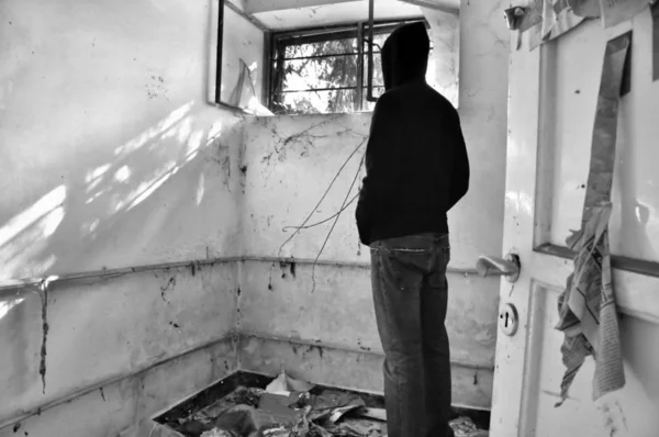 Terk Edilmiş Evin Penceresinden Bakan Kapüşonlu Erkek Figürü Siyah Beyaz — Stok fotoğraf