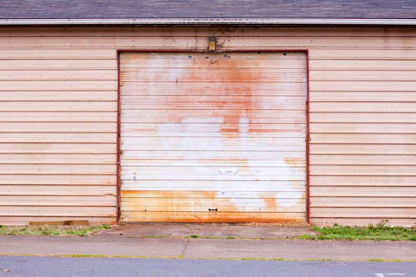 The door of a shed style garage has been painted to cover vandalism and graffiti.